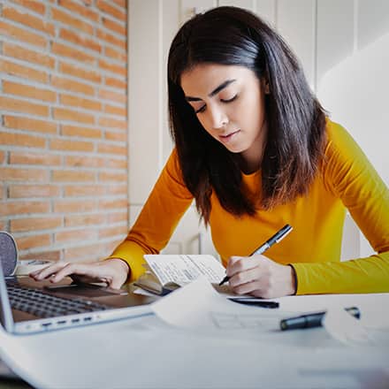 A woman in a yellow shirt working on her college capstone project